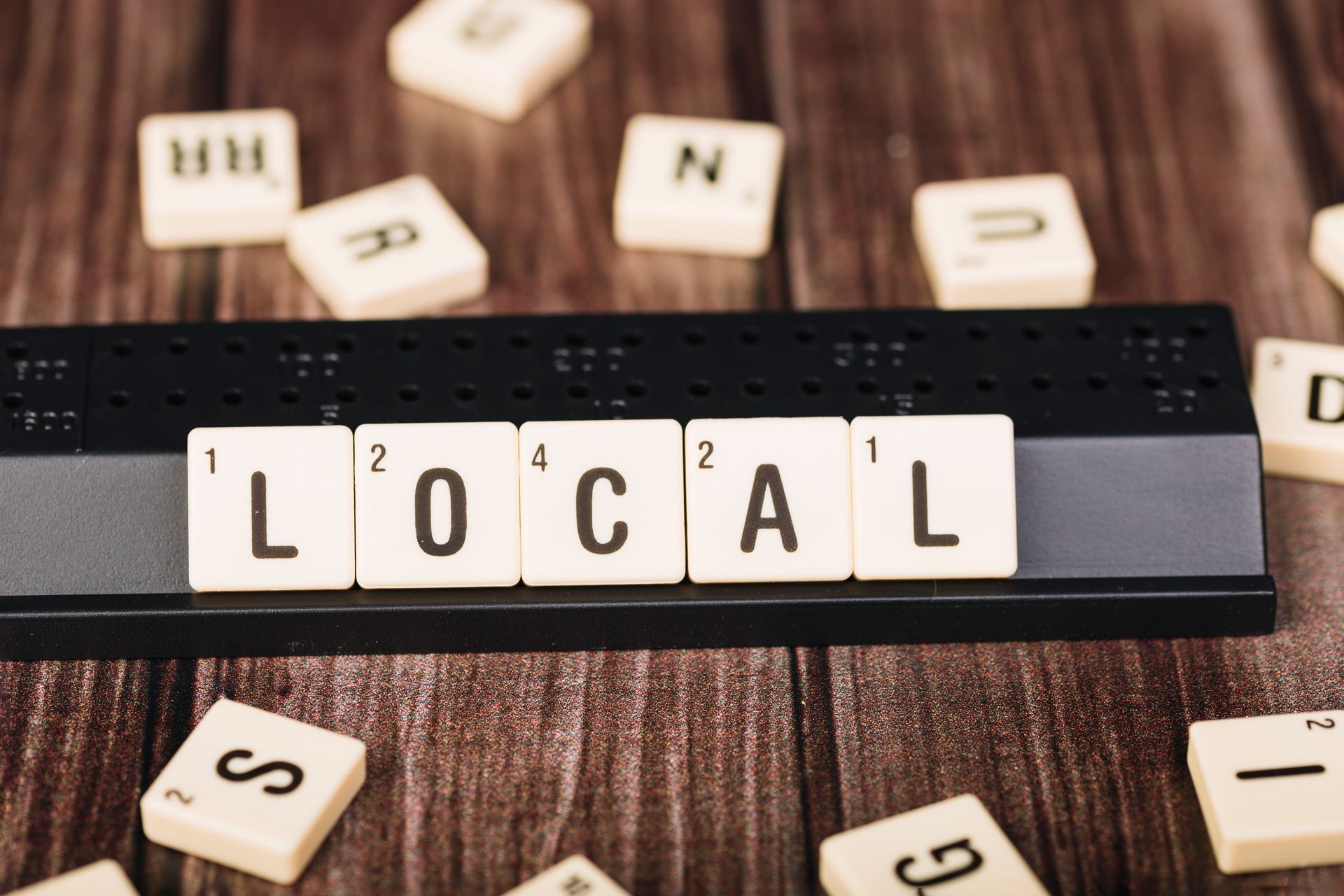 Scrabble tiles spell out the word local on a wooden table