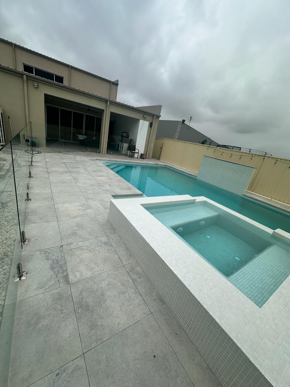A large swimming pool with a hot tub in front of a house.