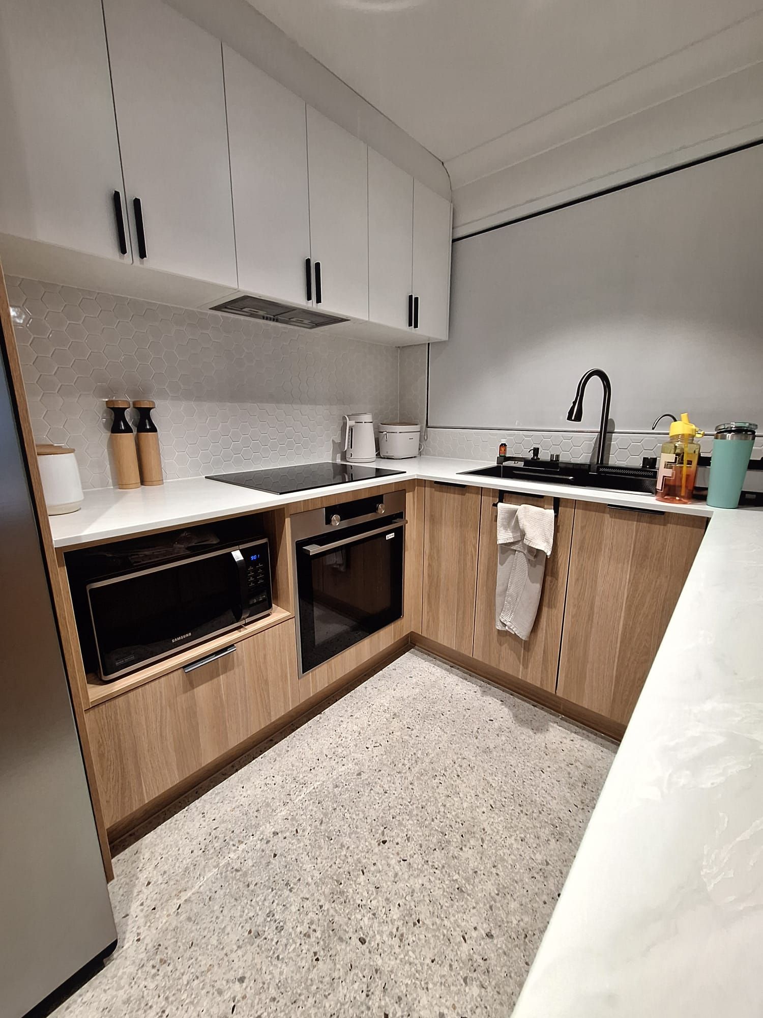 A kitchen with wooden cabinets , stainless steel appliances , a sink , and a refrigerator.