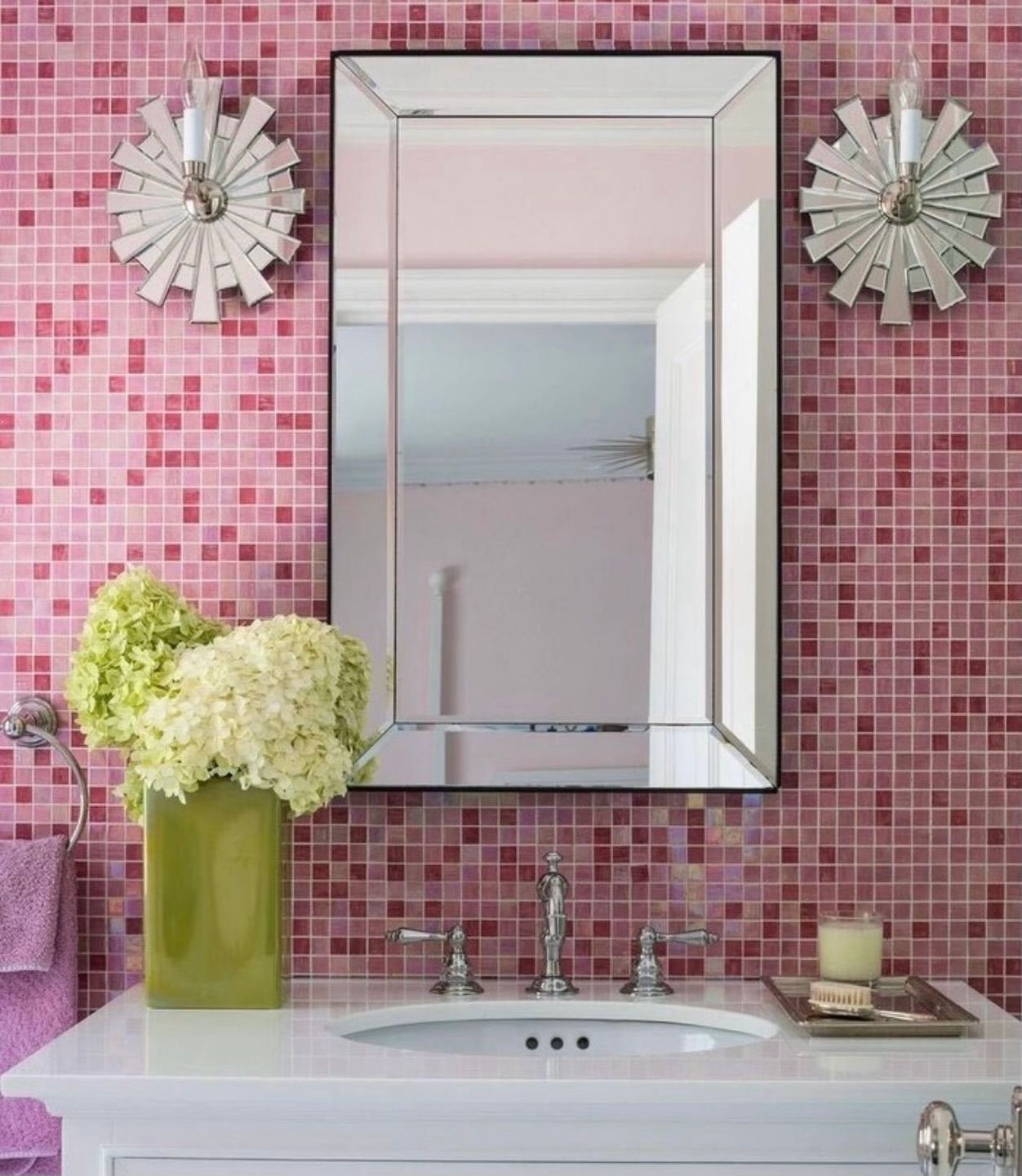 A bathroom with pink tiles and a sink and mirror