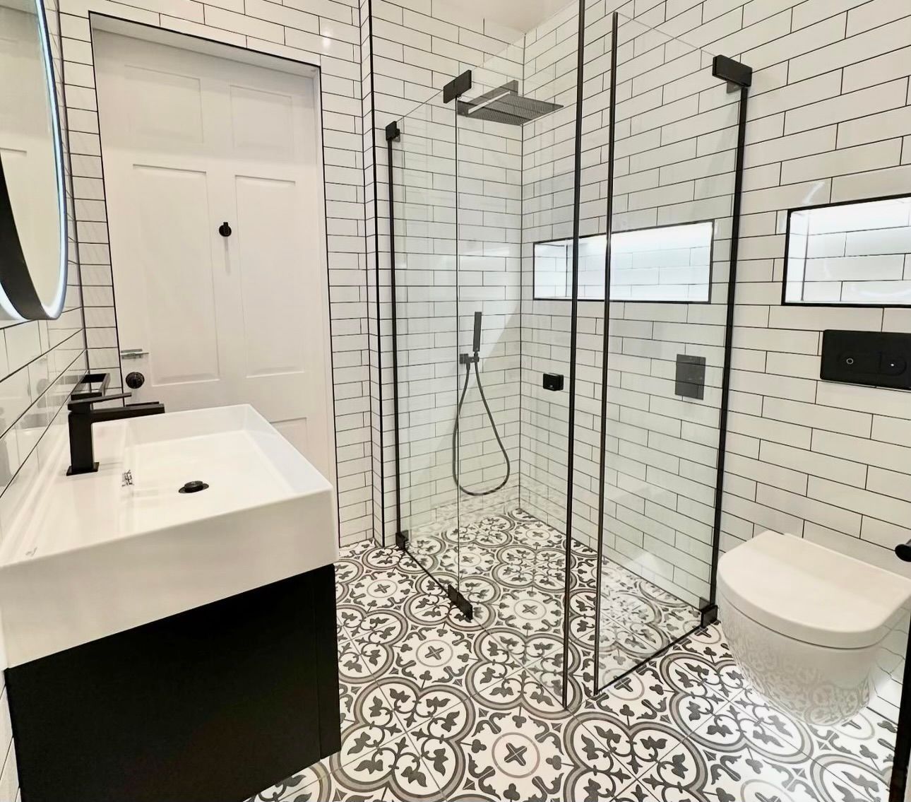 A bathroom with a walk in shower , sink , toilet and mirror.