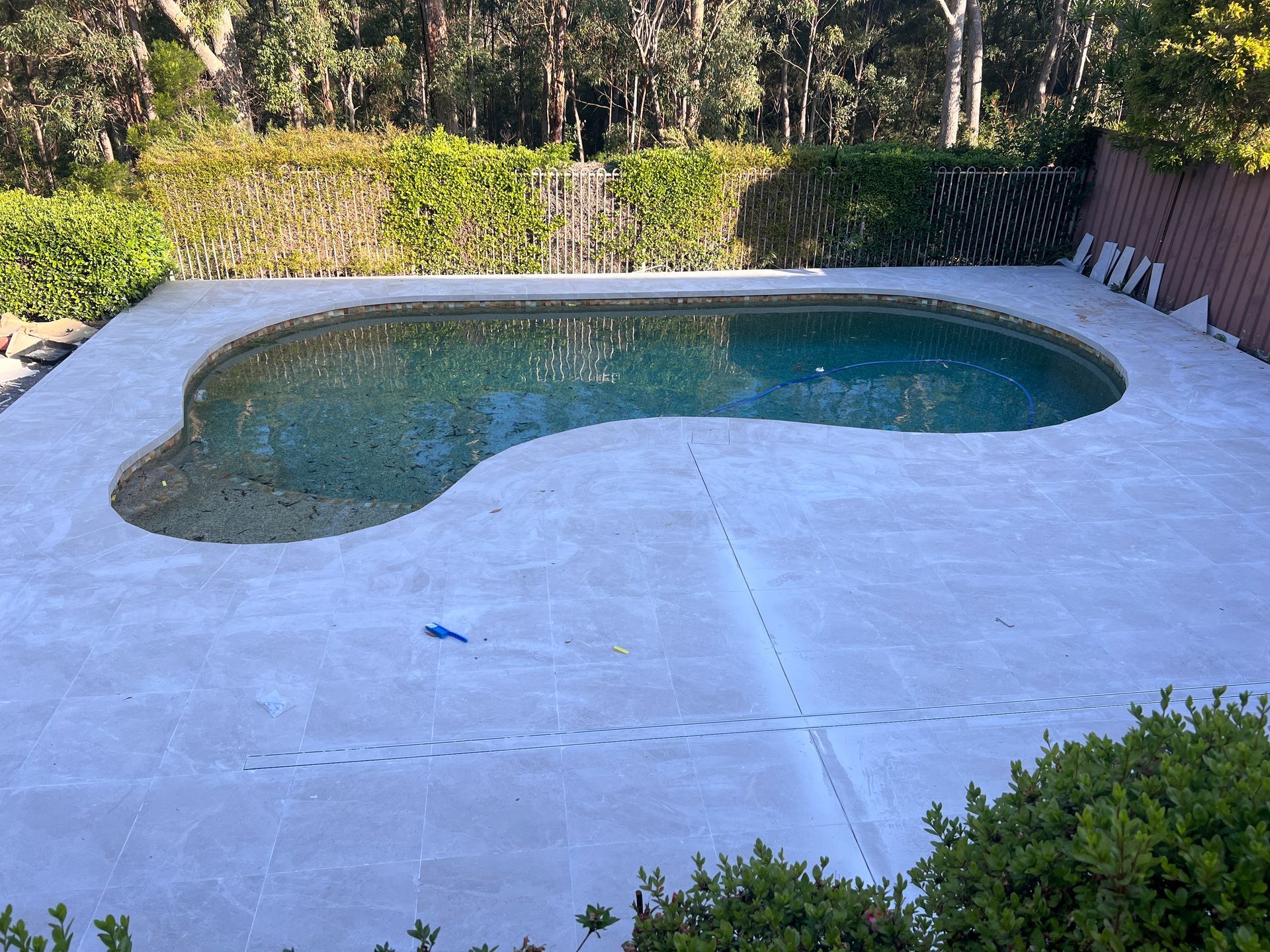 A large swimming pool is sitting on top of a concrete deck.
