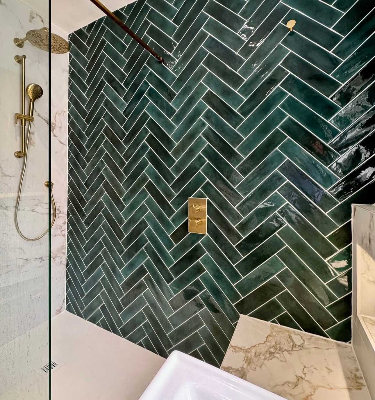 A bathroom with green tiles in a herringbone pattern