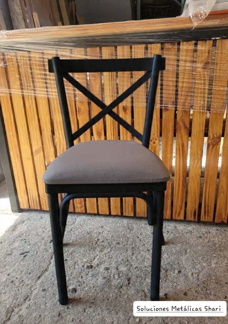 Silla de madera negra con cojín gris frente a una pared de bambú.