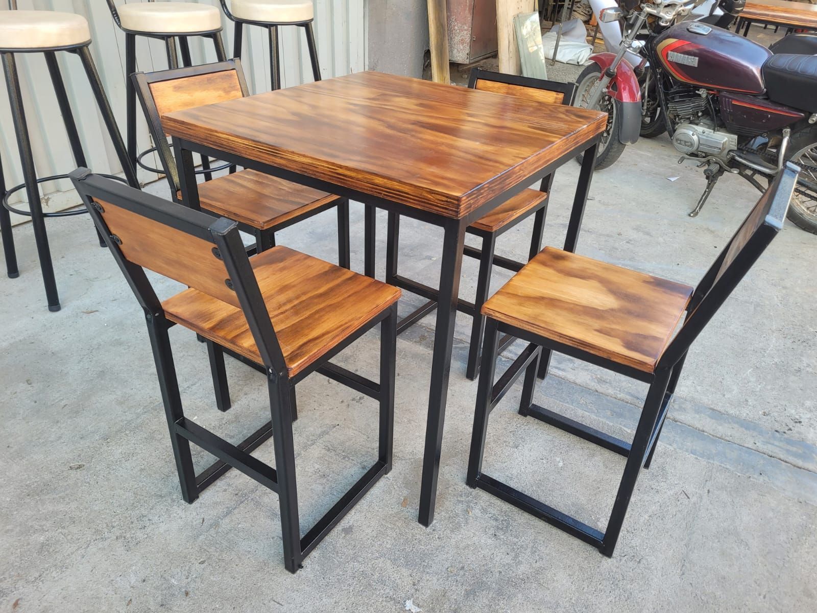 Mesa de madera con dos sillas a juego en una acera al aire libre.