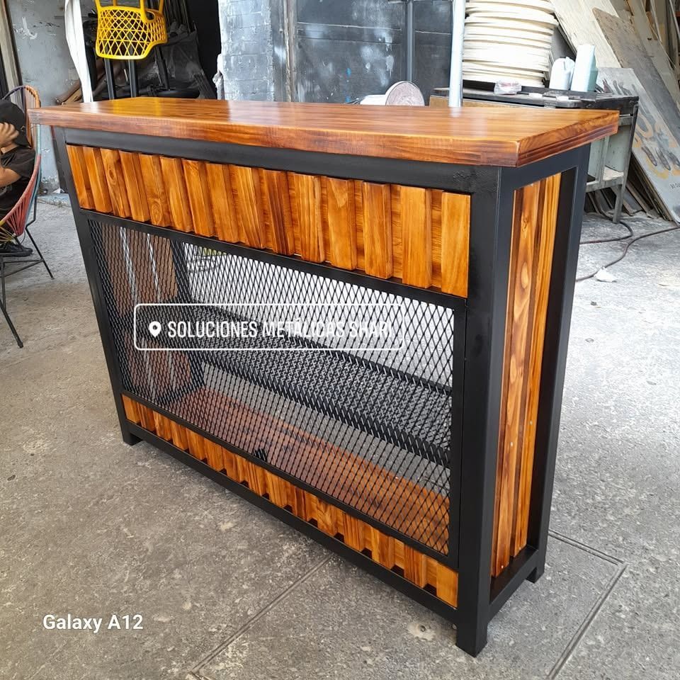 Vitrina de madera y metal negro con frontal de malla en un entorno de taller.