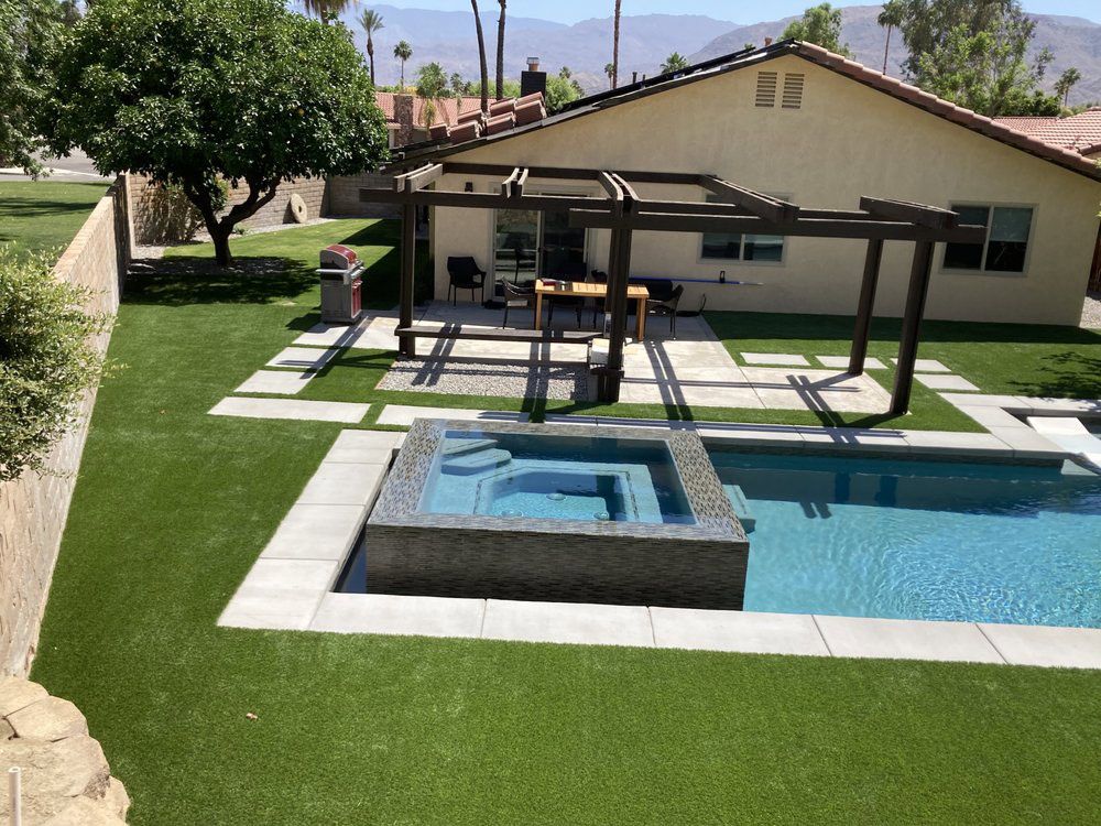 Backyard featuring a swimming pool with an integrated hot tub, patio with a wooden pergola, and a grassy lawn.