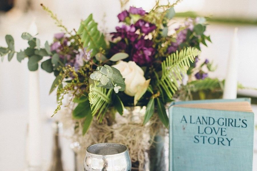 Flowers beside a blue book titled “A Land Girl’s Love Story” on a table