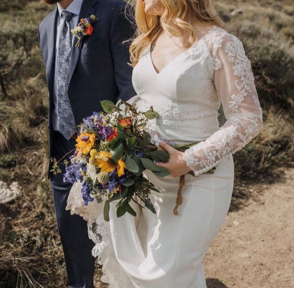 Bride and groom walking outdoors, bride holding a colorful bouquet in a white lace dress