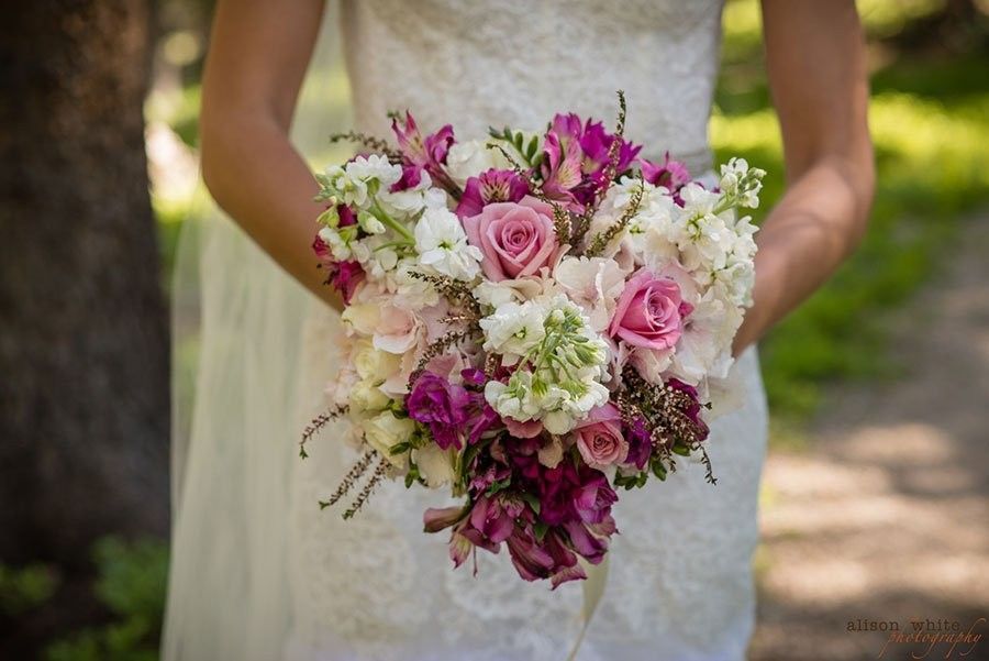 Bride holding pink and white bouquet in a white lace wedding dress