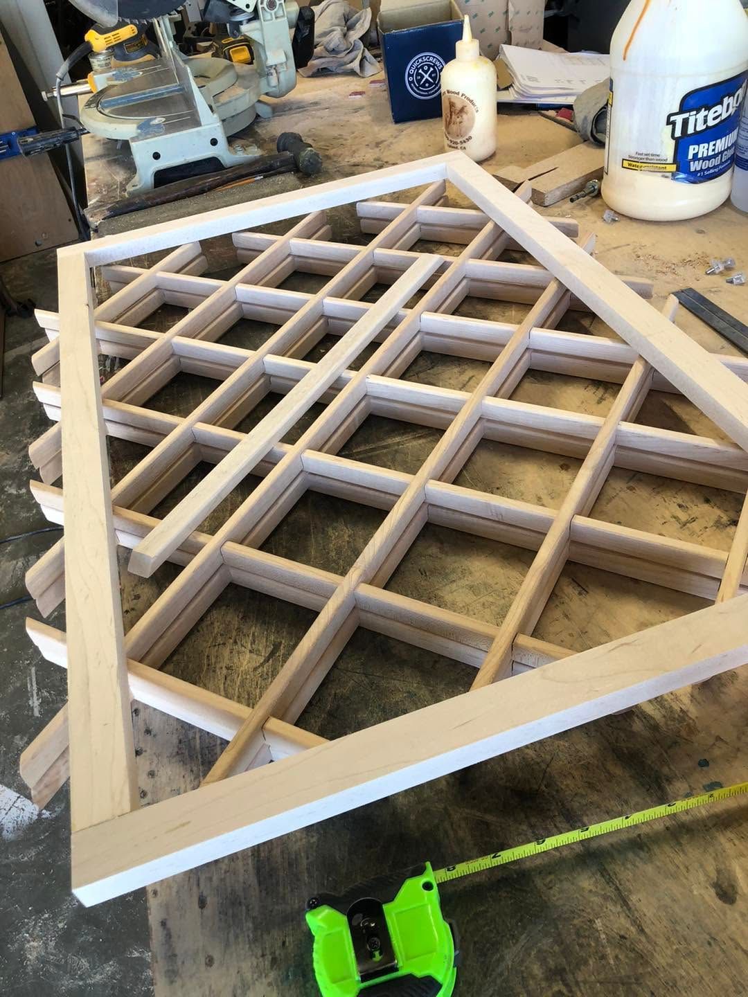 White wooden lattice panel lying on a workbench in a workshop, with tools and paint cans nearby