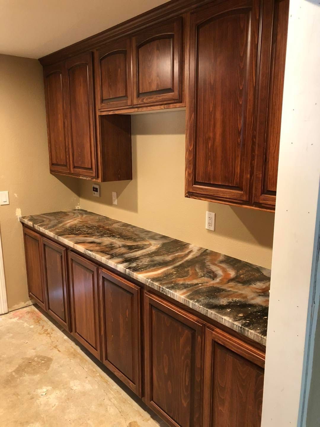 Dark wood built-in cabinets with a marbled countertop in an unfinished room.