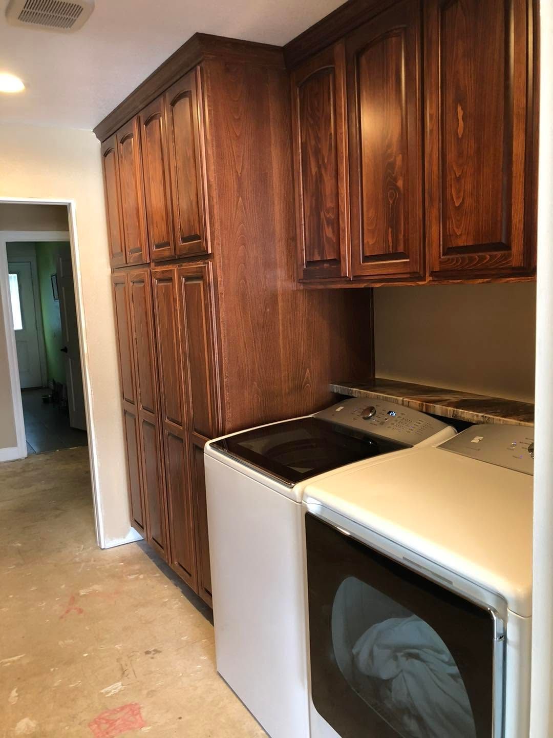 Kitchen hallway with tall dark wood cabinets, a stove, and a white washer/dryer against the wall.