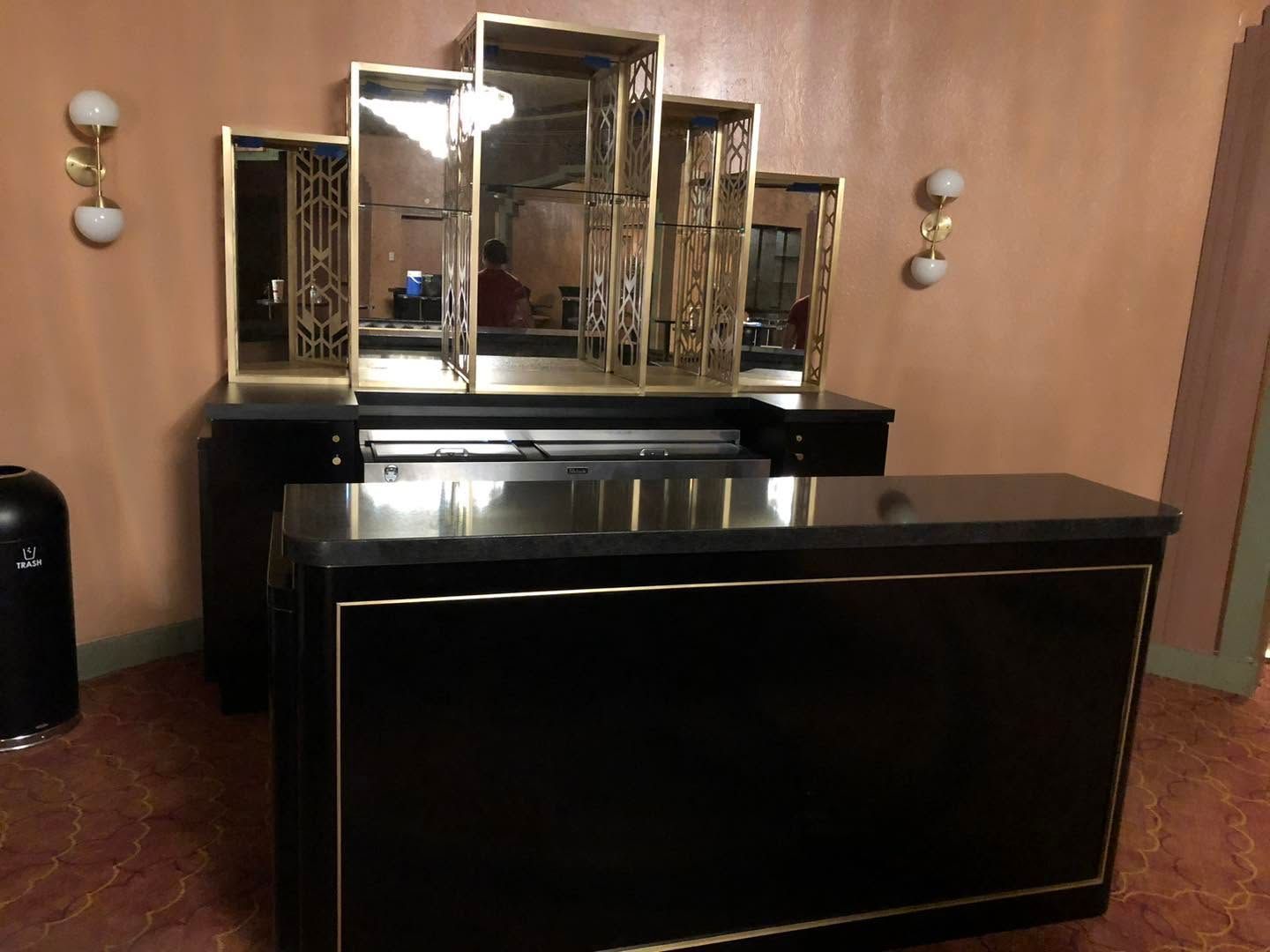 Empty room with black reception desk and mirrored shelving against wood-paneled walls