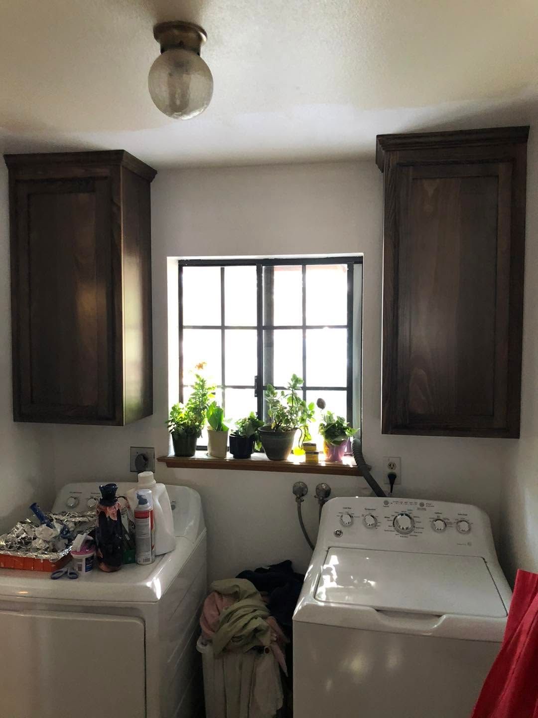 Laundry room with washer and dryer, window, plants, and dark wall cabinets