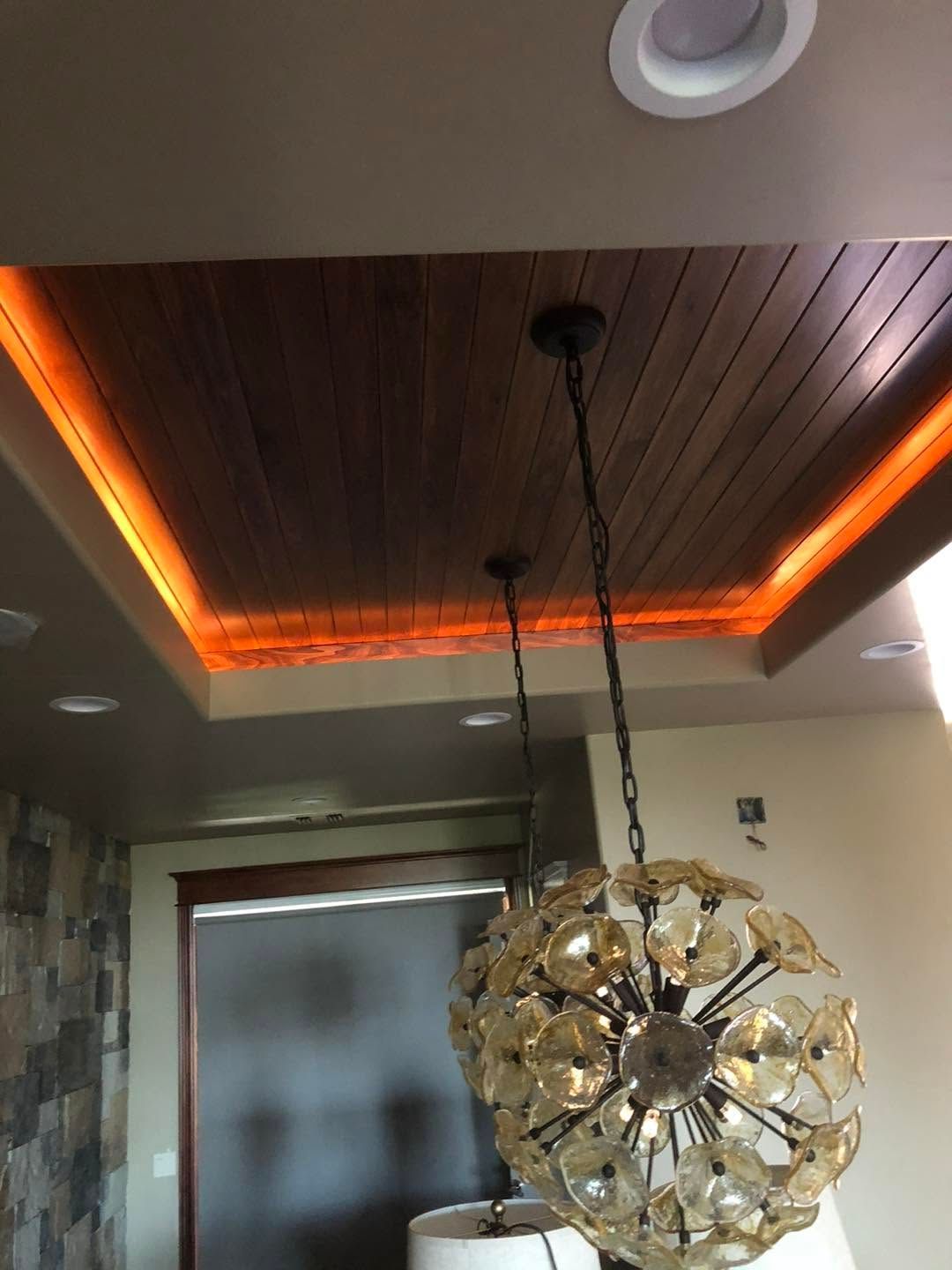 Ceiling with warm orange LED cove lighting and a hanging spherical pendant lamp above a doorway