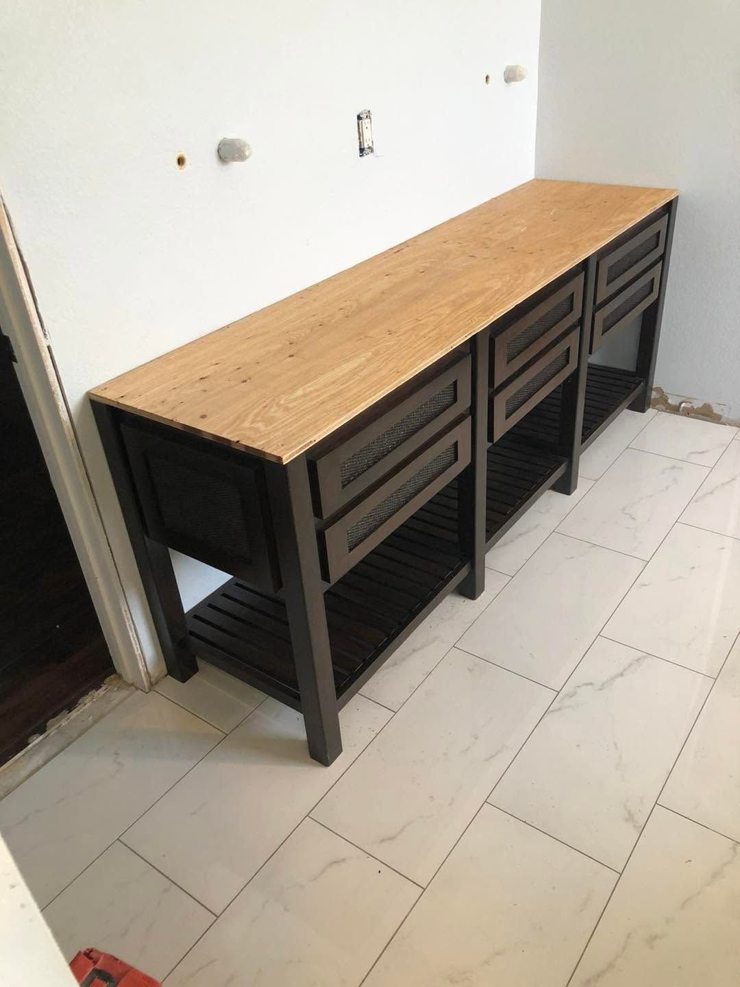 Long wooden counter with dark metal cabinets against a white tiled wall in an empty room