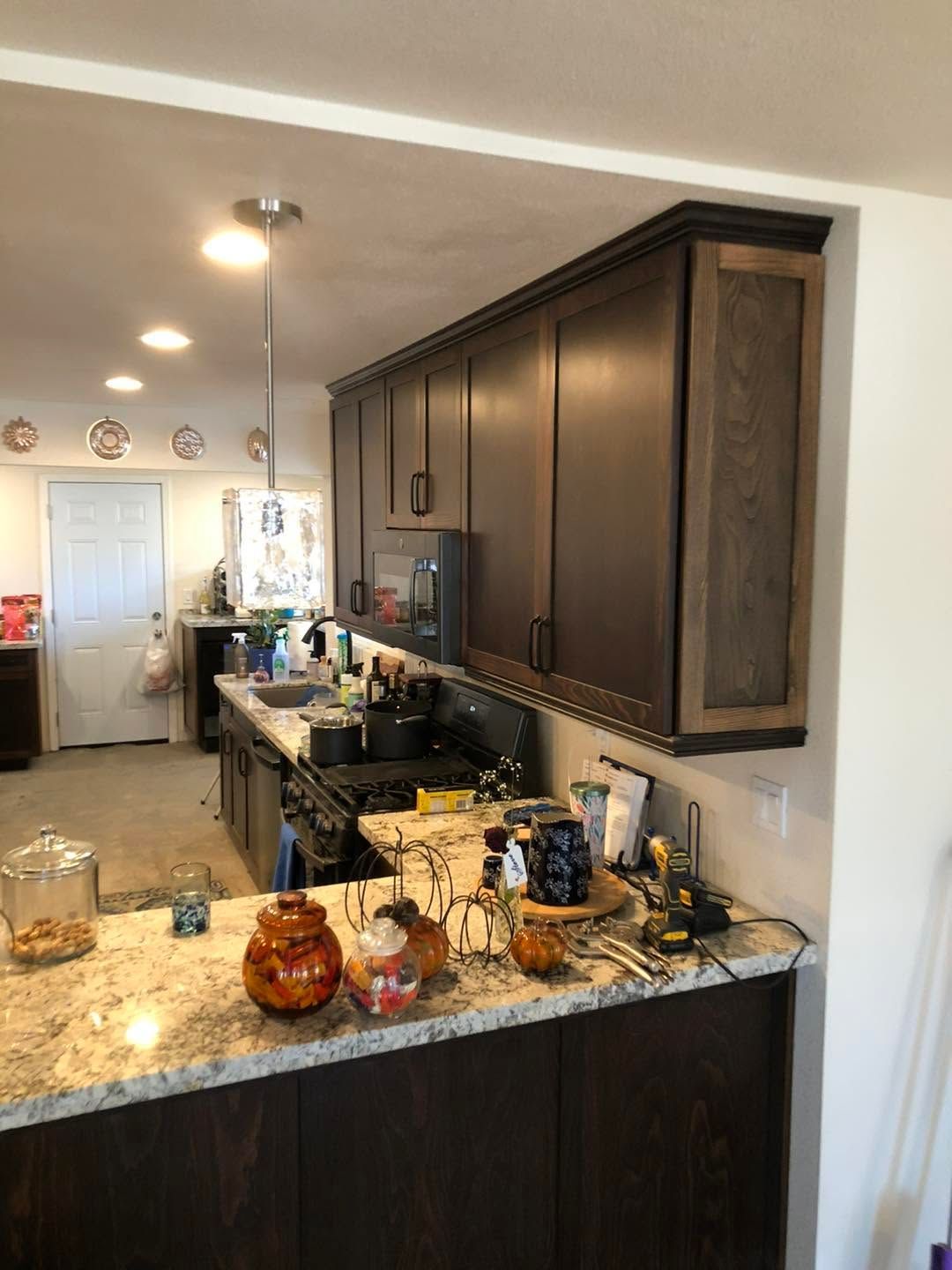 Kitchen with dark wood cabinets, granite island, and sink, viewed from the counter toward a bright dining area.