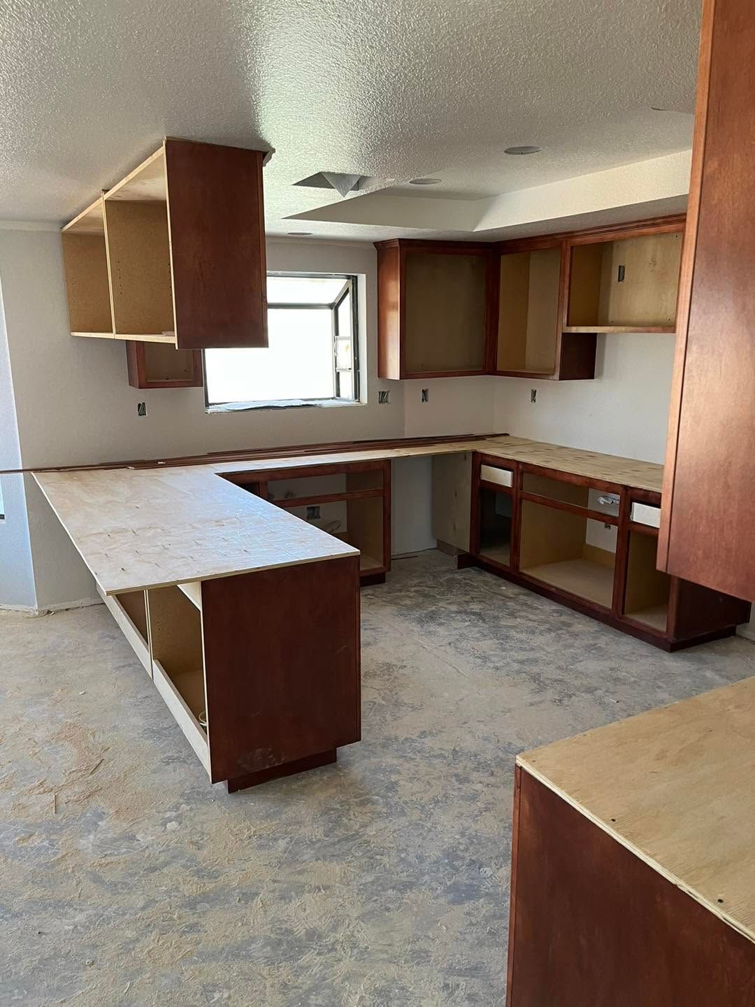 Empty kitchen with unfinished wooden cabinets, laminate counters, and a window above the sink area