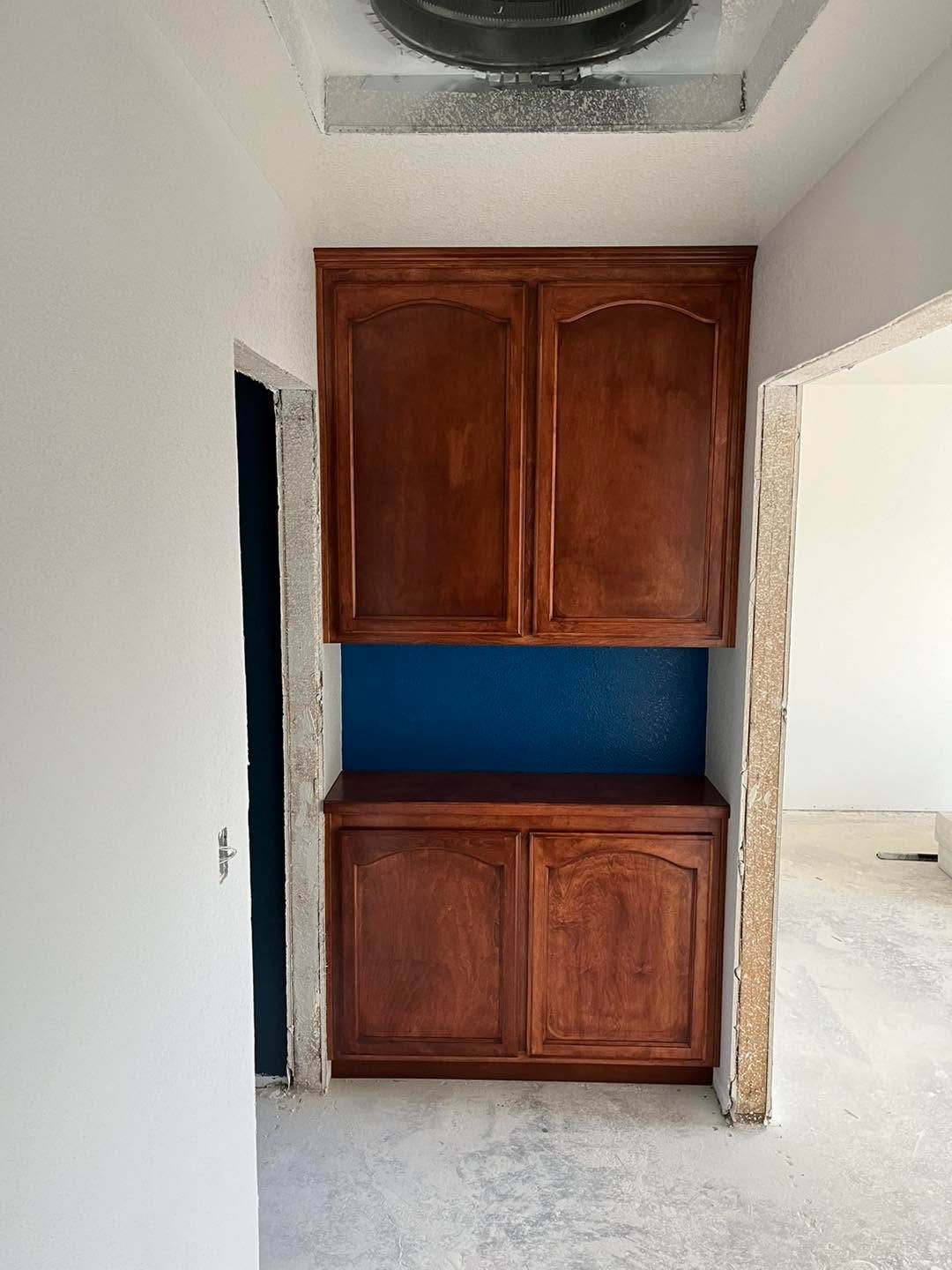 Kitchen alcove with wooden upper and lower cabinets and a blue backsplash between them