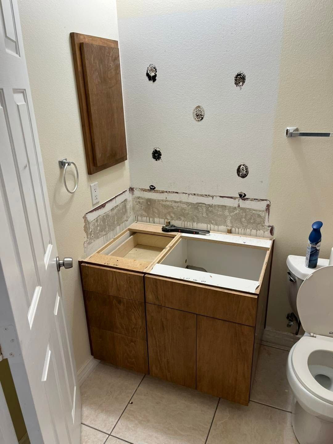 Small bathroom with unfinished wooden vanity and sink under construction, next to a toilet and tiled floor.