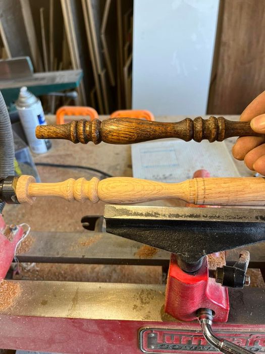 Two wooden turned pieces clamped in a workshop vise, one dark-stained and one unfinished light wood.