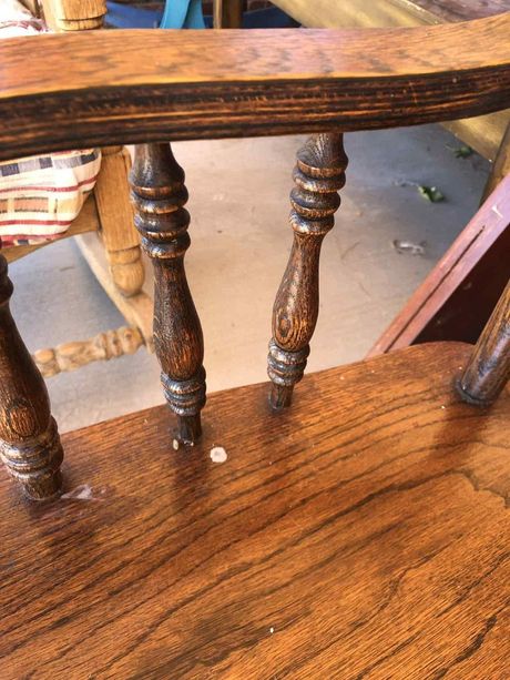 Close-up of a wooden chair with turned spindles and a scratched wood seat