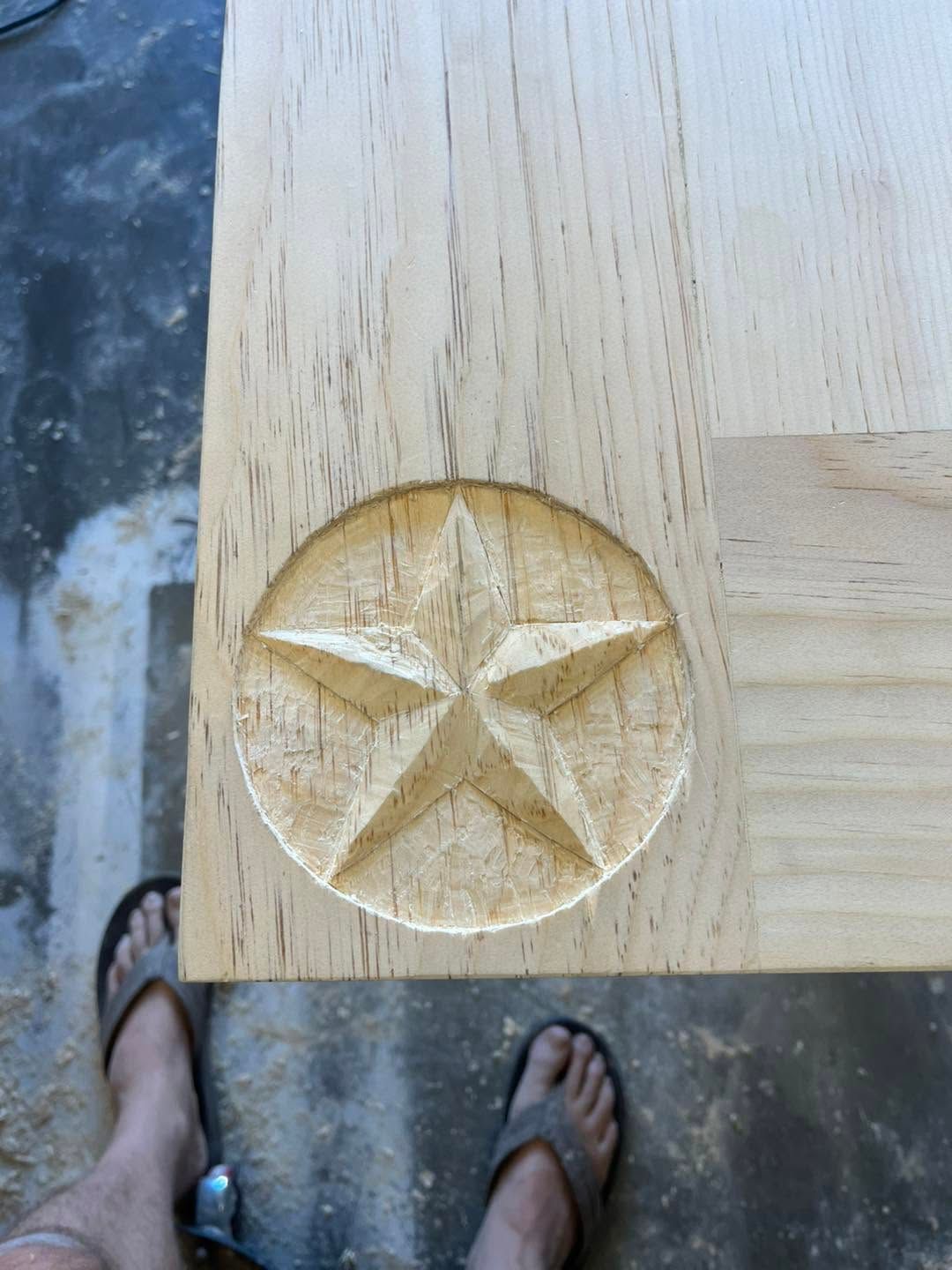 Wooden post corner with a carved star medallion in a circular recess, viewed from above.