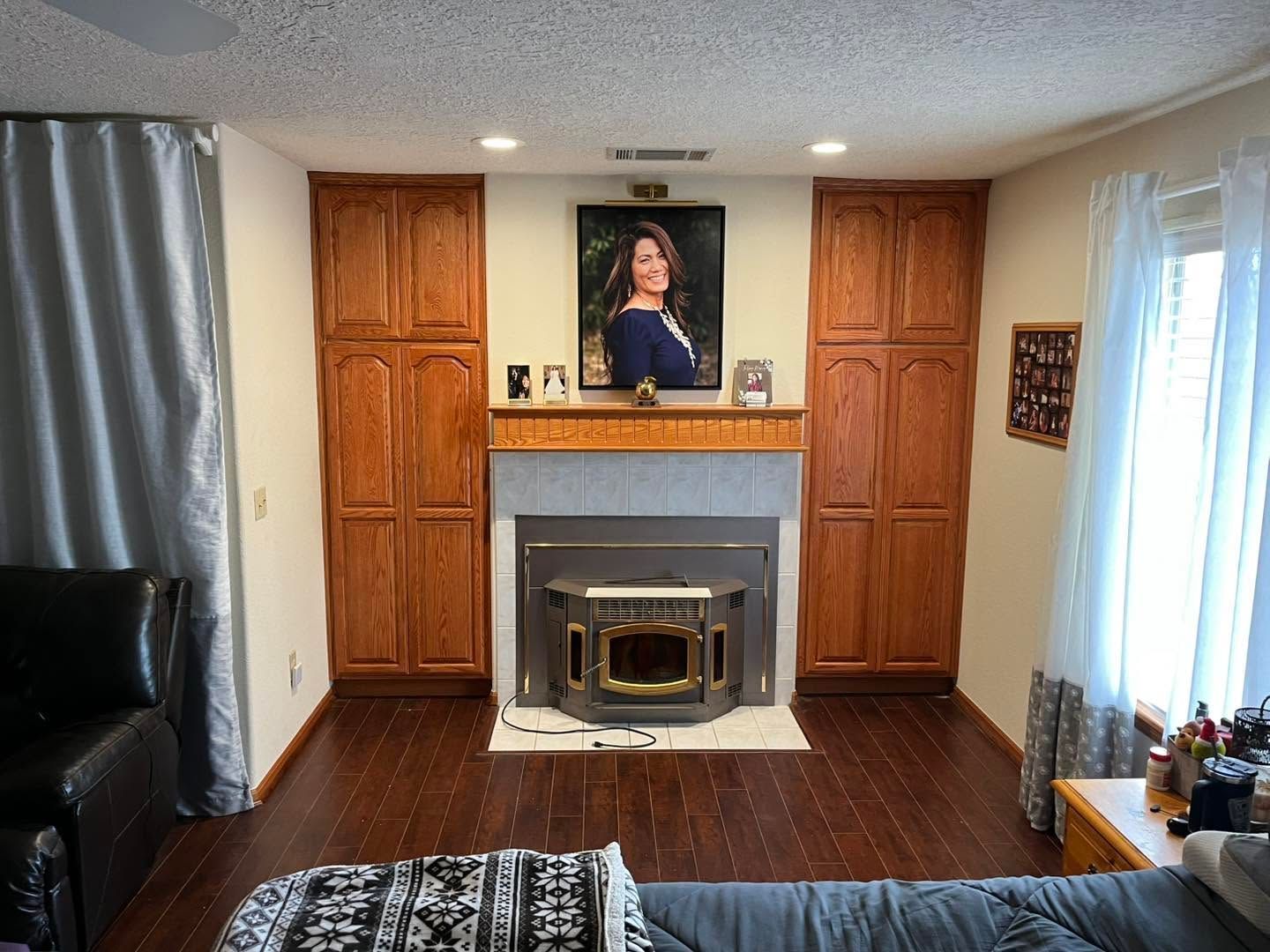 Living room with fireplace, wooden cabinets, and a portrait above the mantel.