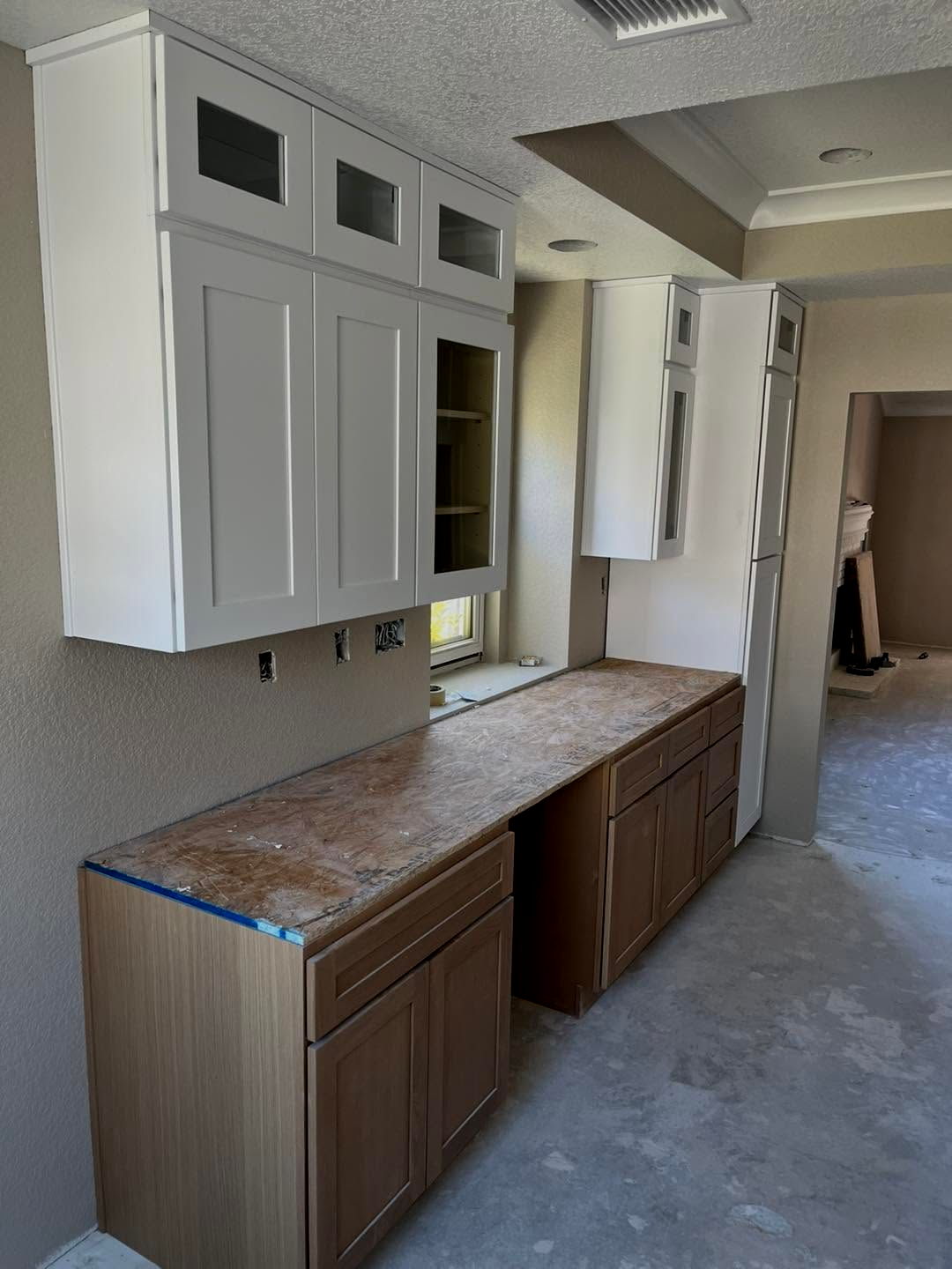 Kitchen hallway with white cabinets, wood countertops, and brown lower cabinets under renovation