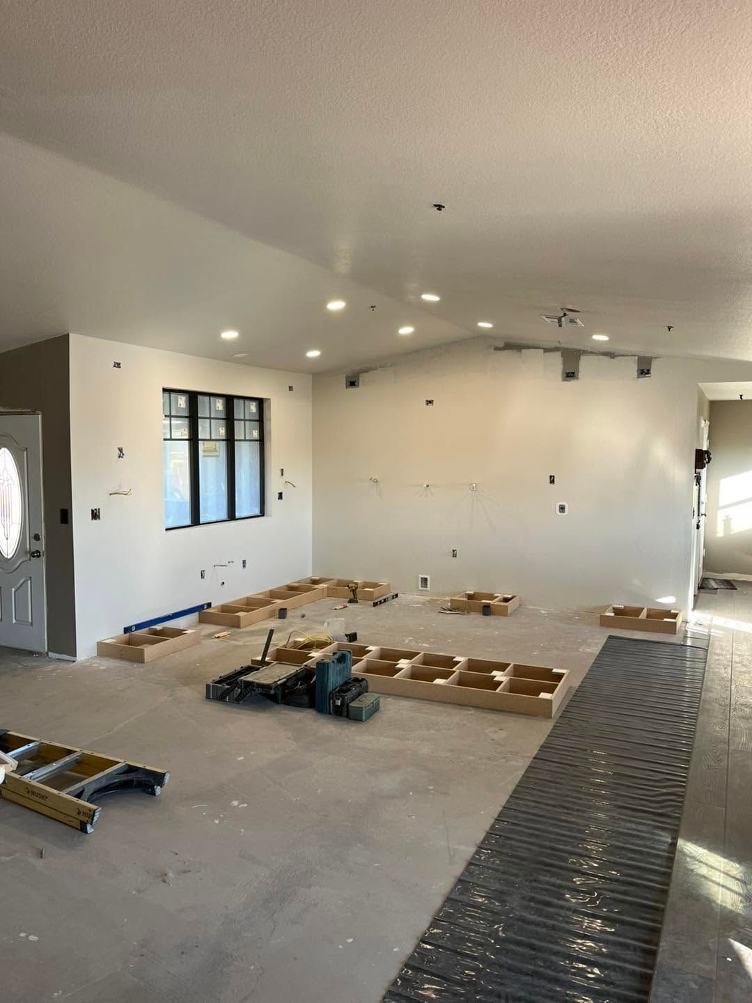 Partially renovated living room with tools, open flooring, recessed lights, and windowed wall