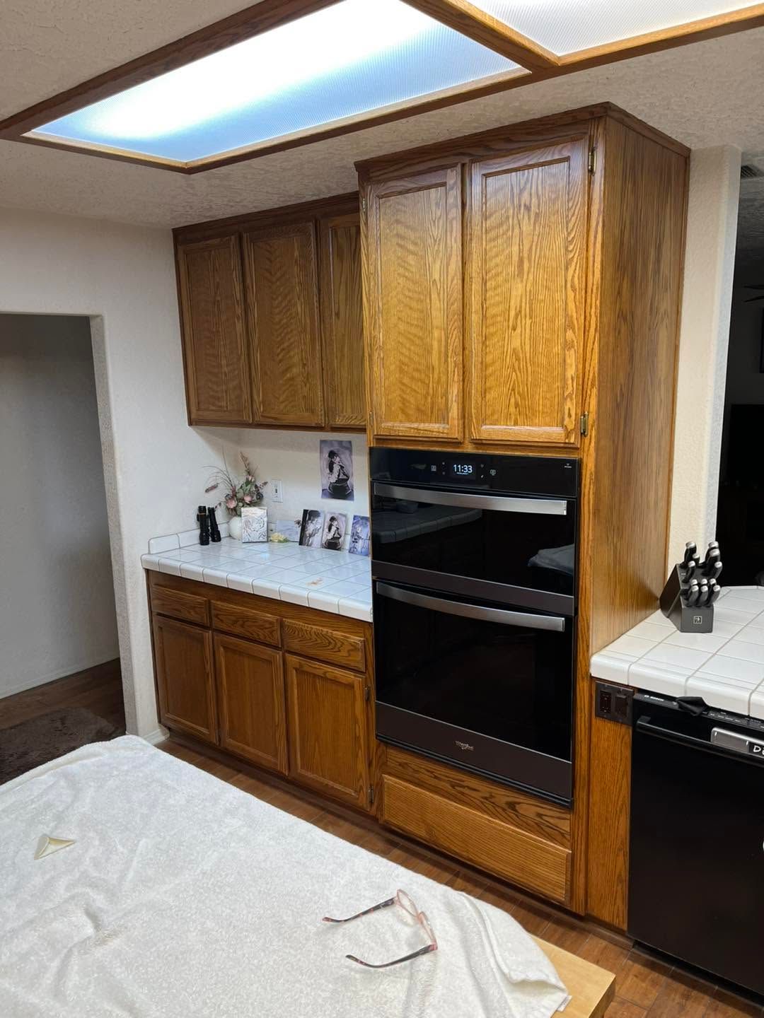 Wood-paneled kitchen with built-in oven, white countertops, and dark appliances