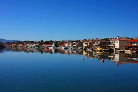 Calm waterfront town with colorful houses reflected in a still blue harbor under a clear sky