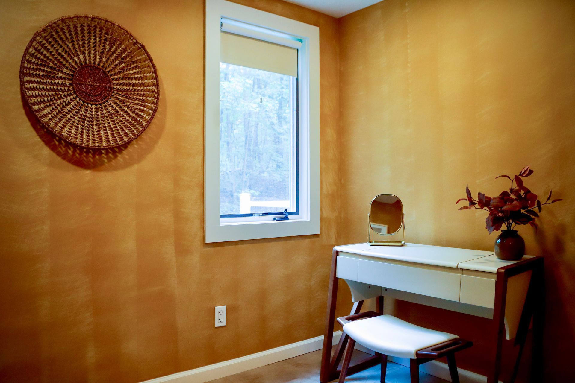 A room with a desk , chair , mirror and window.