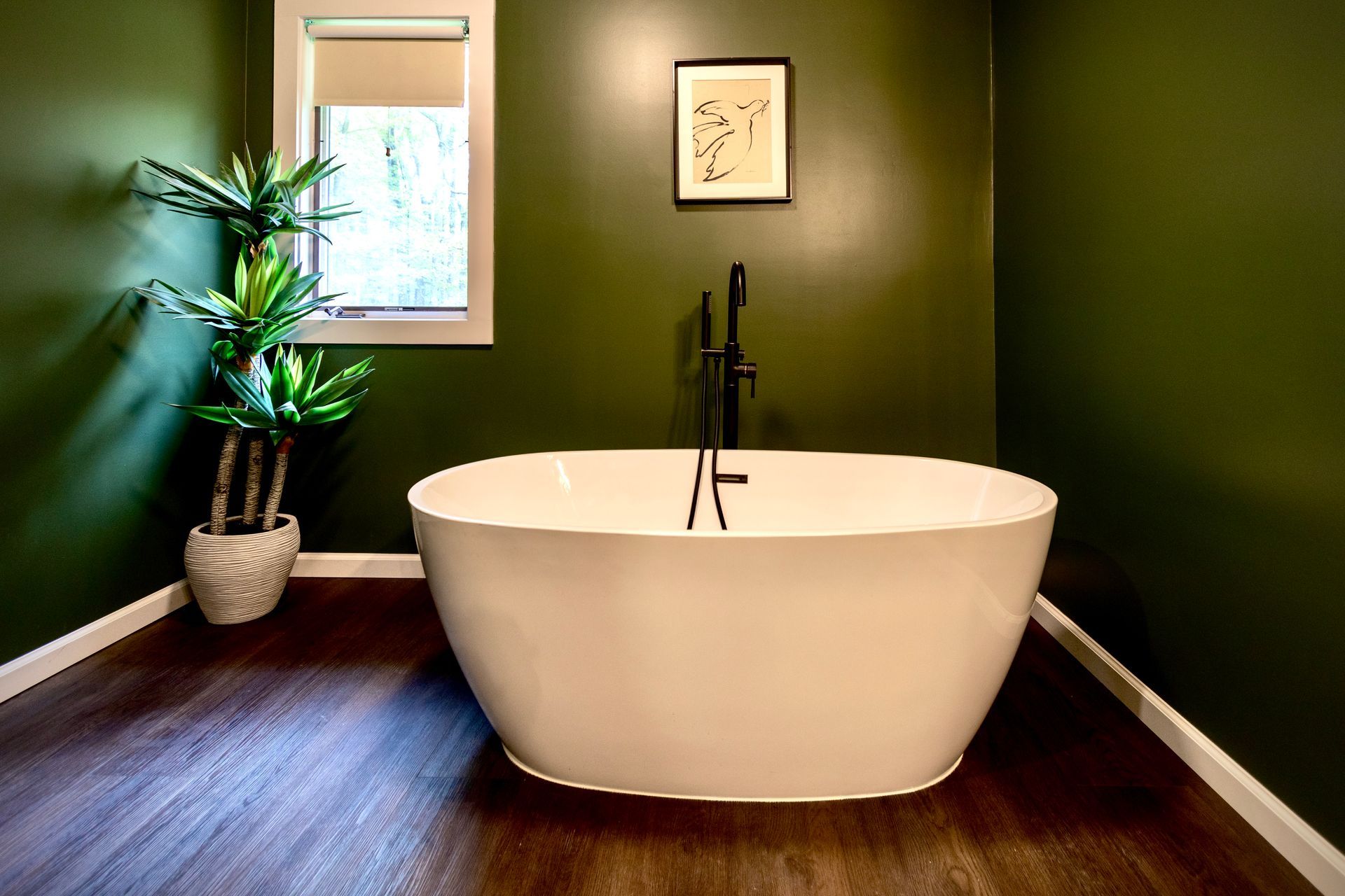 A bathroom with green walls and a white bathtub