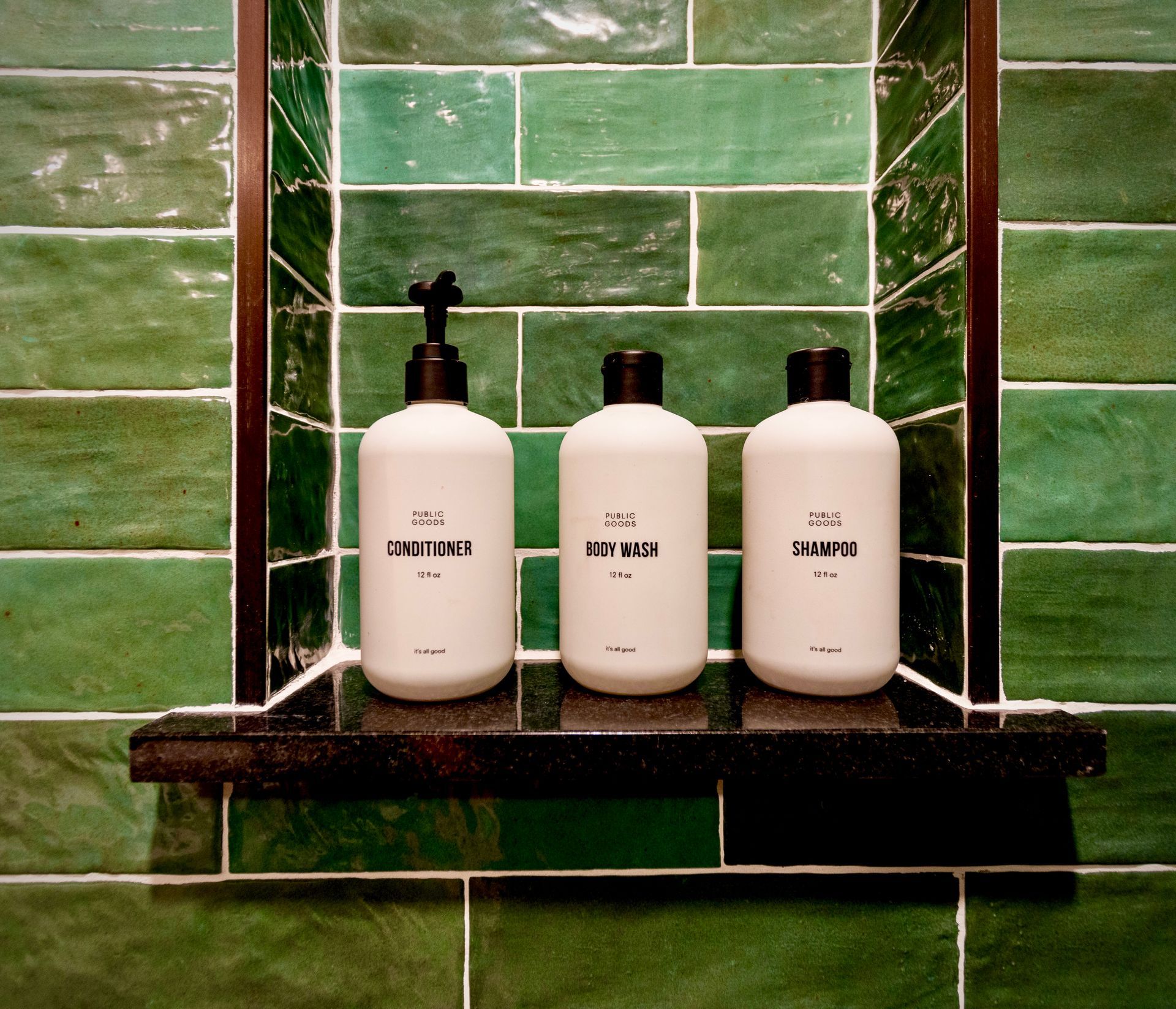 Three bottles of lotion are on a shelf in a bathroom