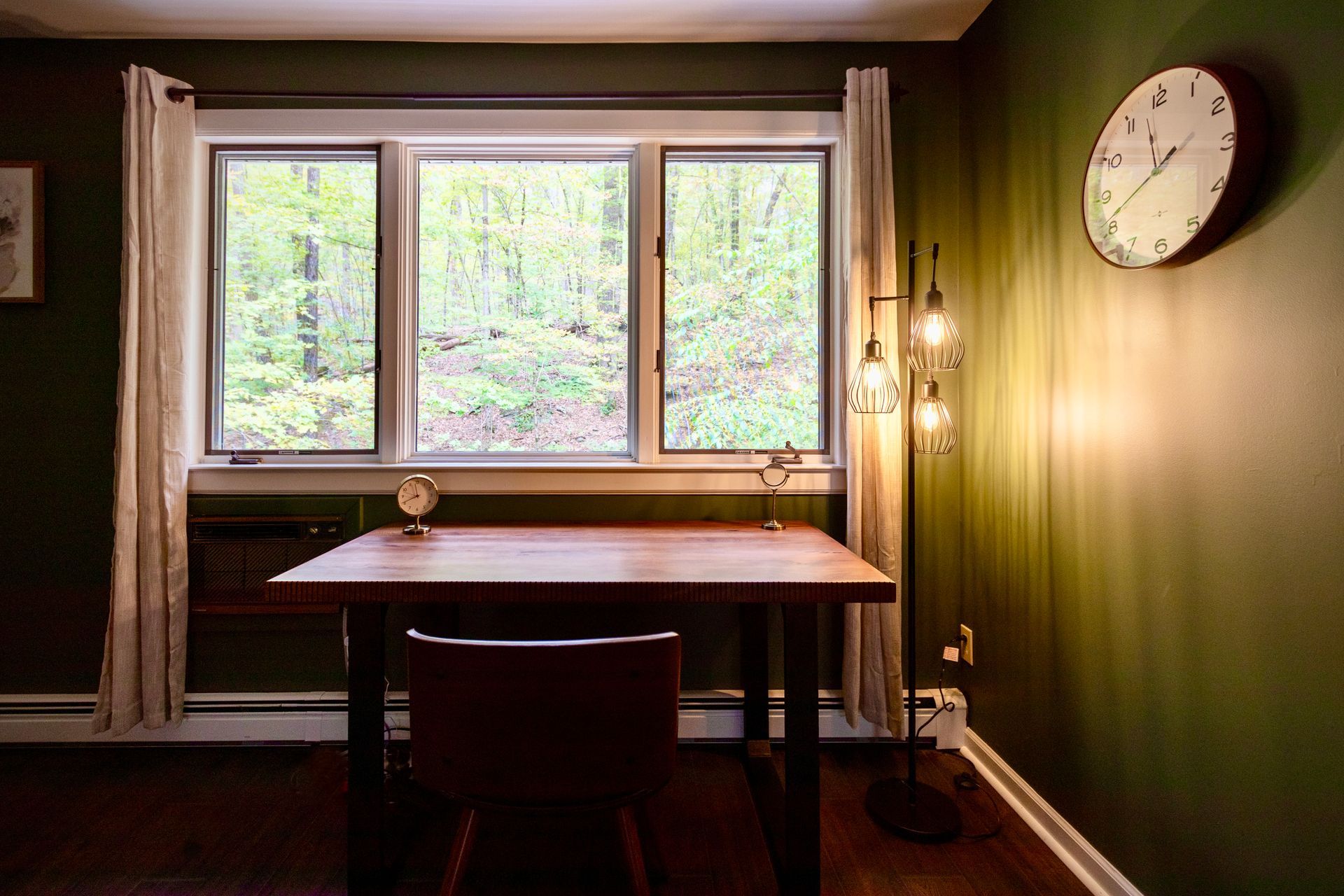 There is a clock on the wall above the desk in the room.