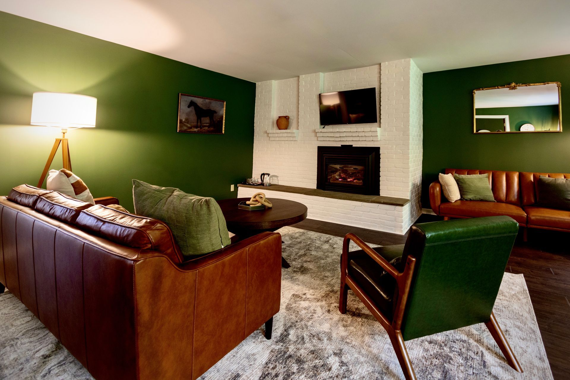A living room with green walls , brown furniture , a fireplace and a television.