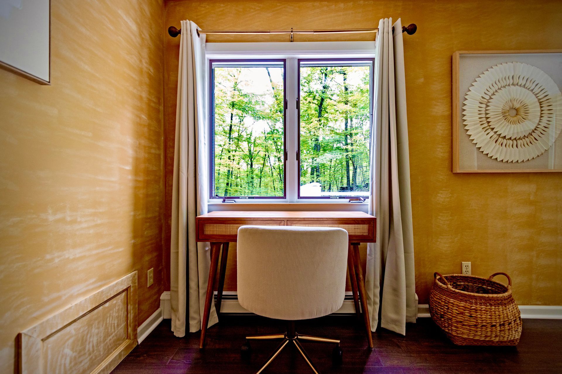 A room with a desk and chair in front of a window.