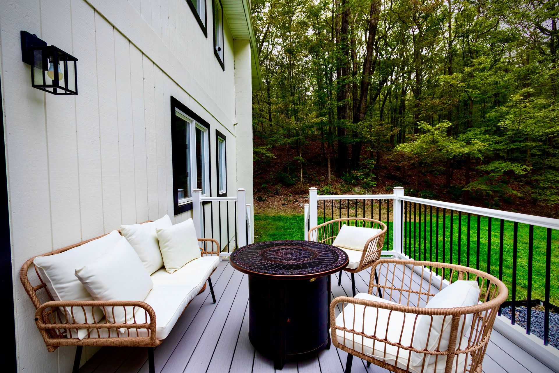 There is a fire pit on the deck with a couch and chairs.
