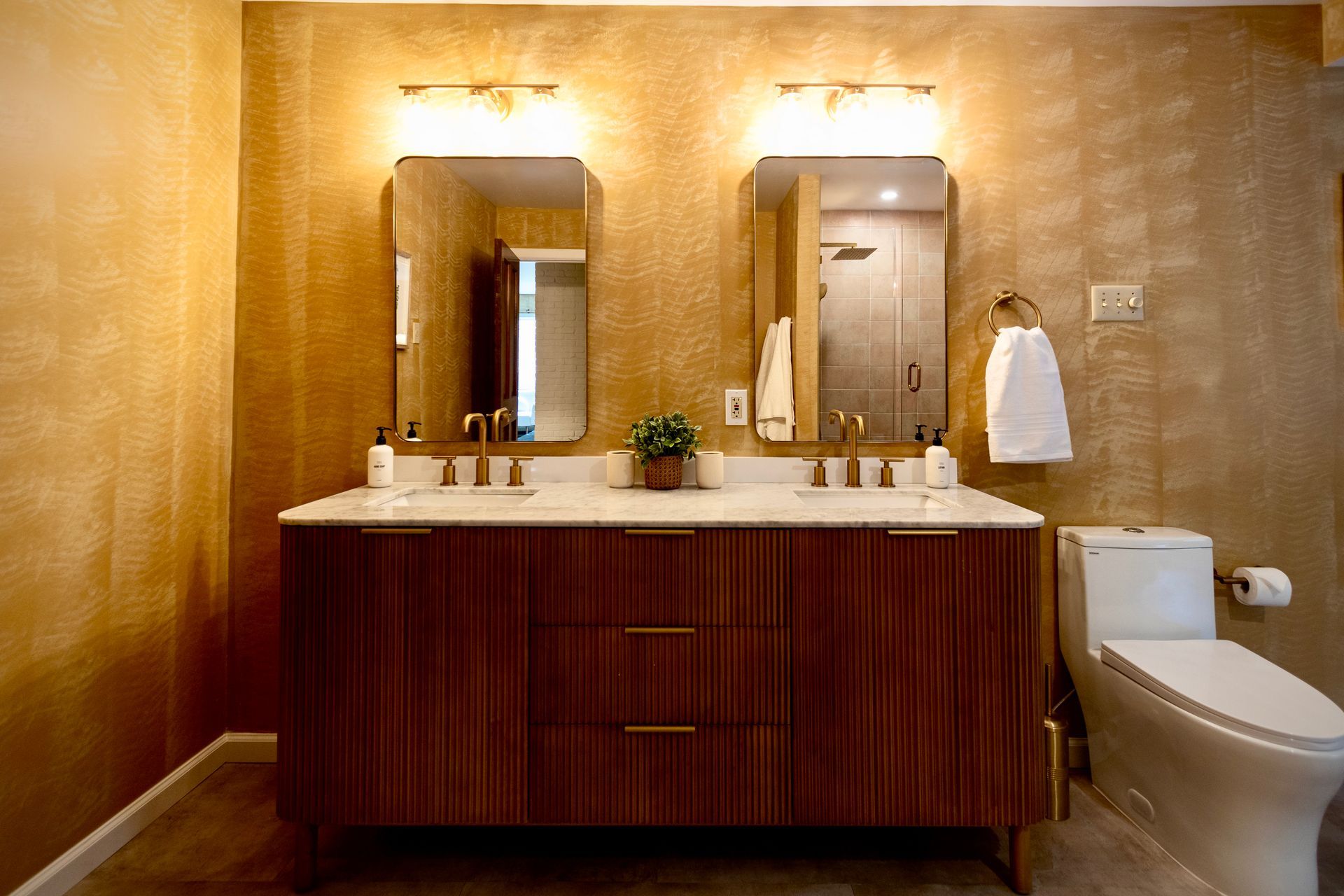 A bathroom with two sinks , a toilet , and two mirrors.