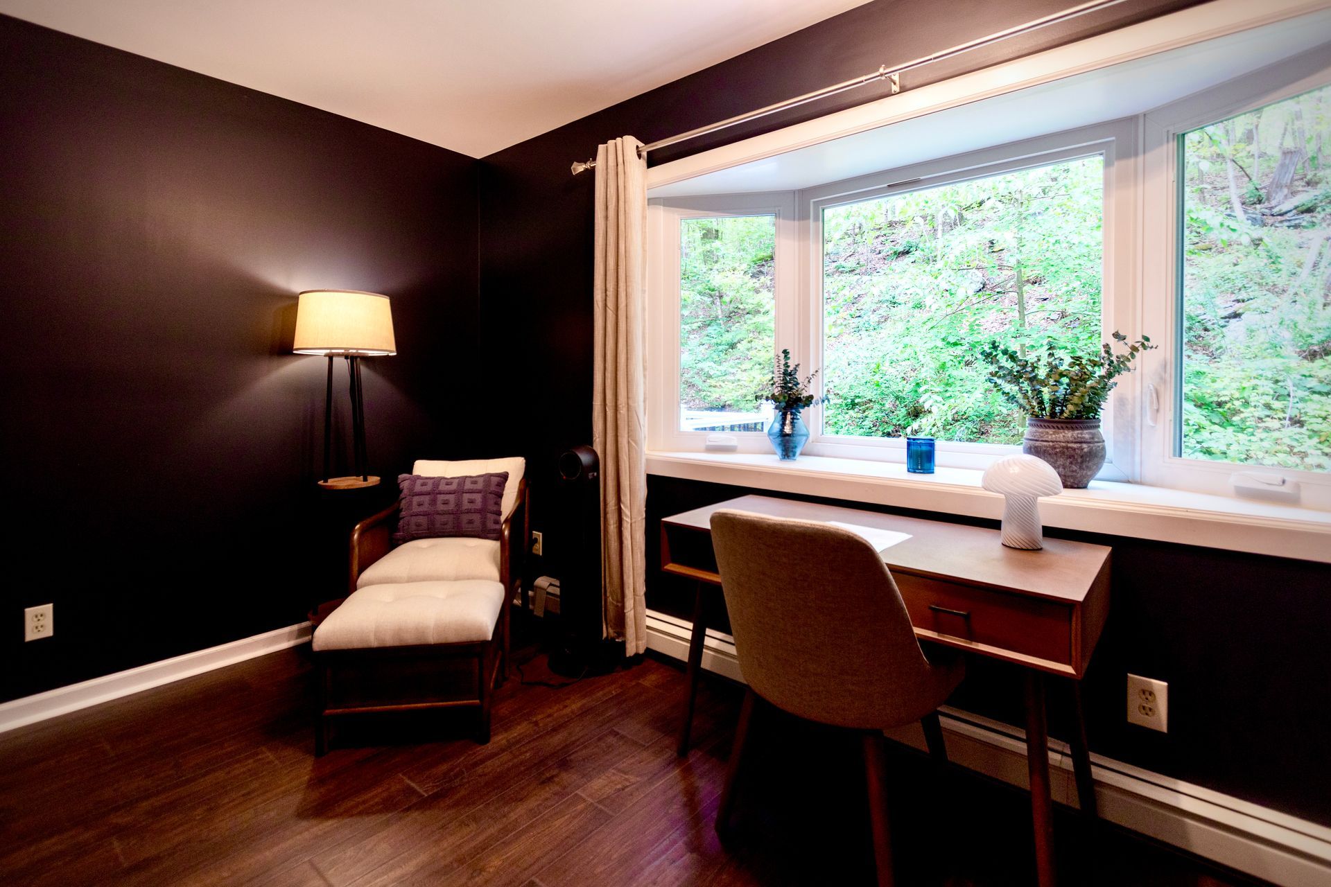 A room with a chair and a desk in front of a window.