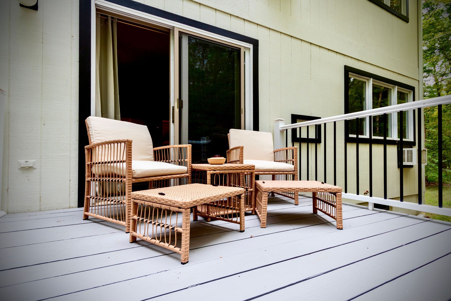 A deck with wicker furniture and a sliding glass door
