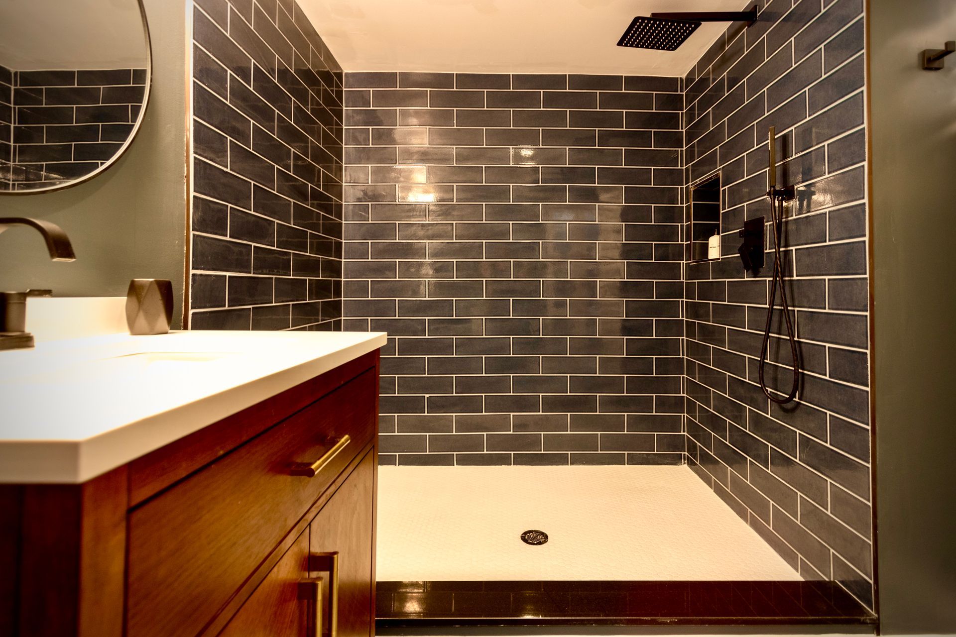 A bathroom with a walk in shower , sink and mirror.