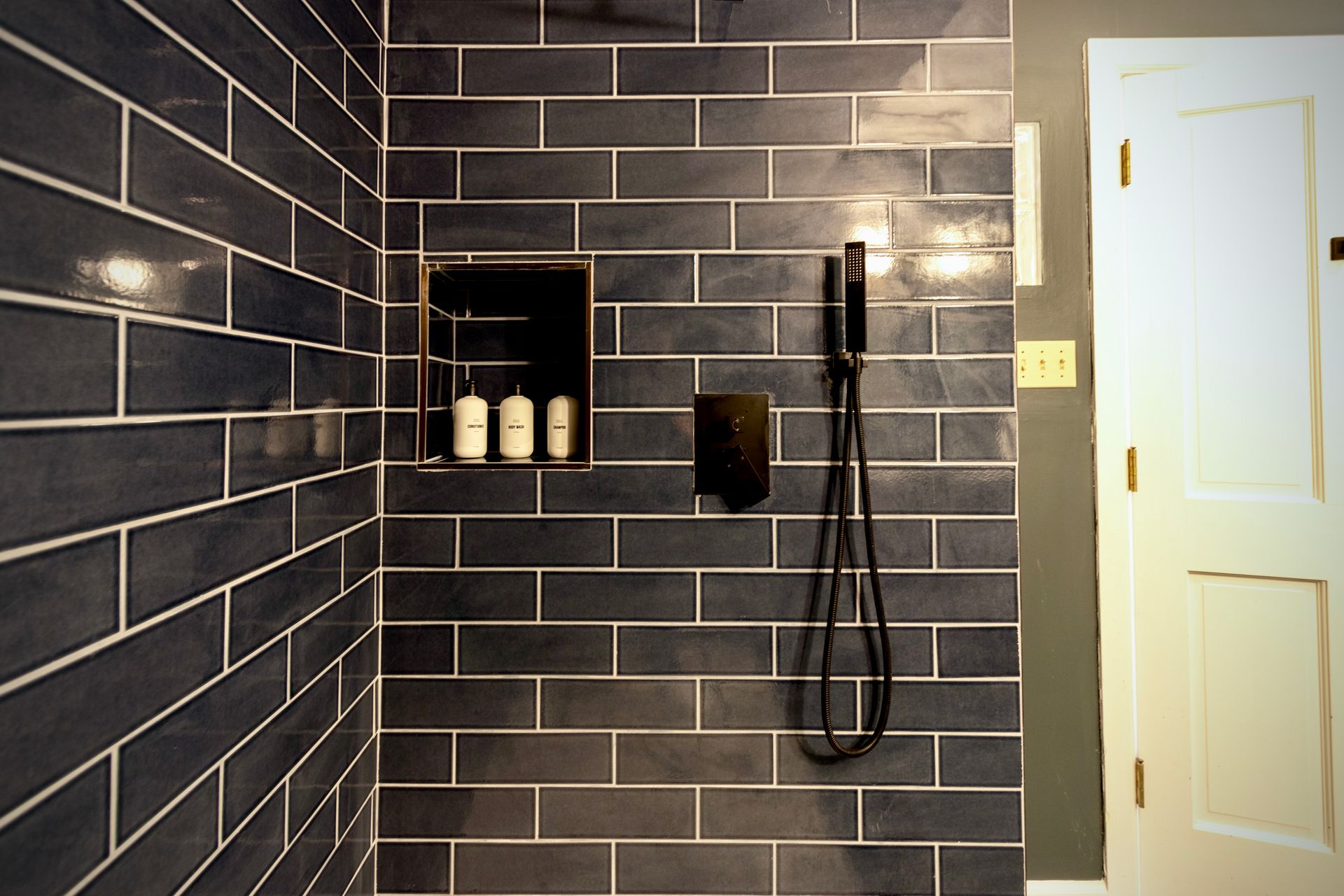 A bathroom with black tiles and a shower head
