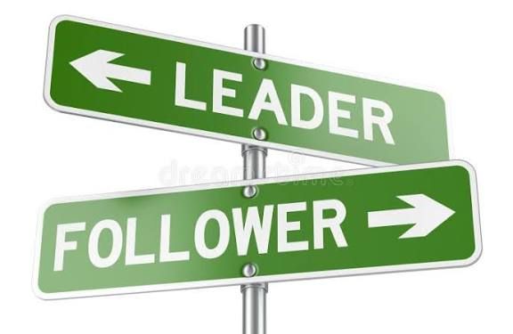 Green road signs labeled “LEADER” left and “FOLLOWER” right on a pole