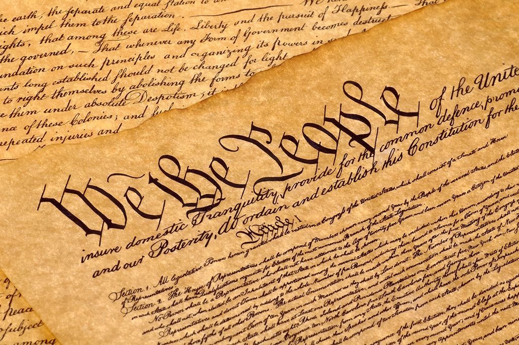 Close-up of the U.S. Constitution with the words “We the People” visible on aged parchment.