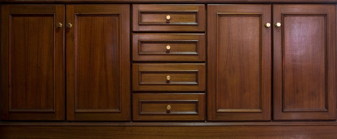 Wooden bathroom vanity with two doors and four drawers. Brown.