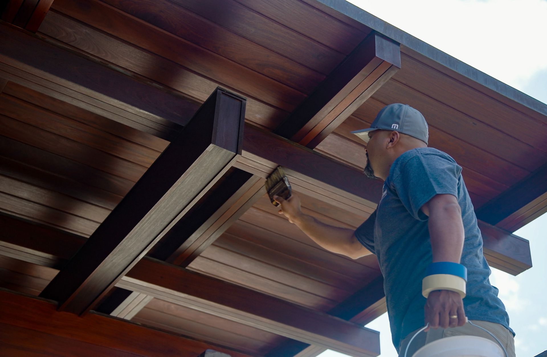 Person painting a wooden ceiling outdoors.