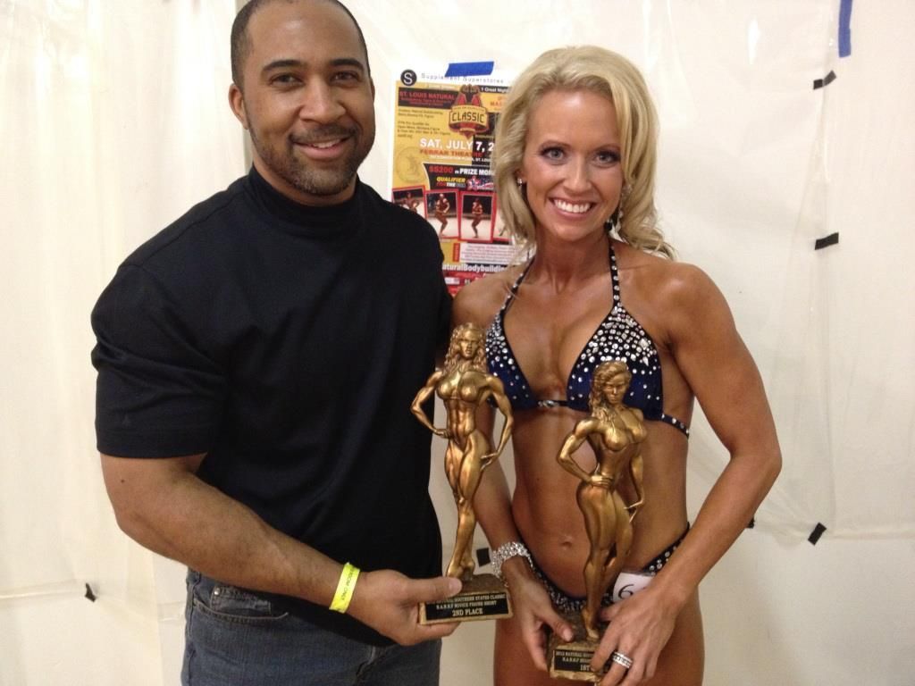 A man and a woman are posing for a picture holding trophies